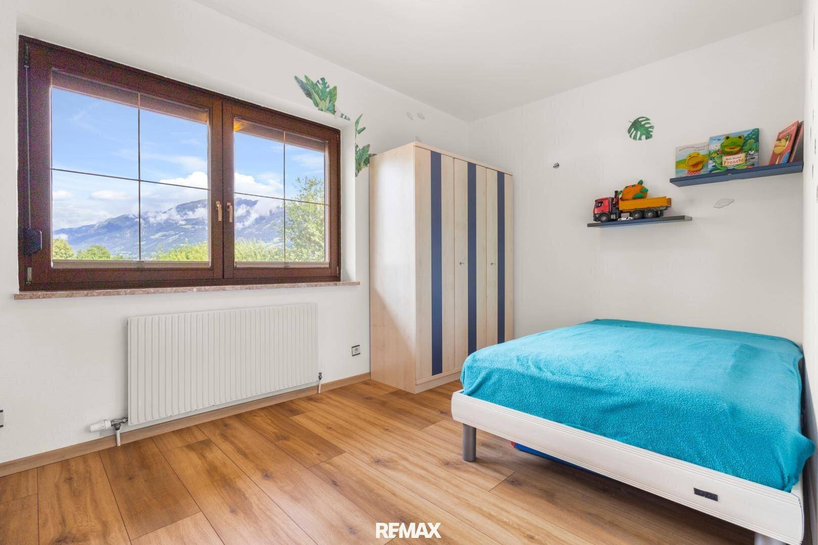 Kinderzimmer mit Einzelbett, Holzboden und Fenster mit Bergblick.