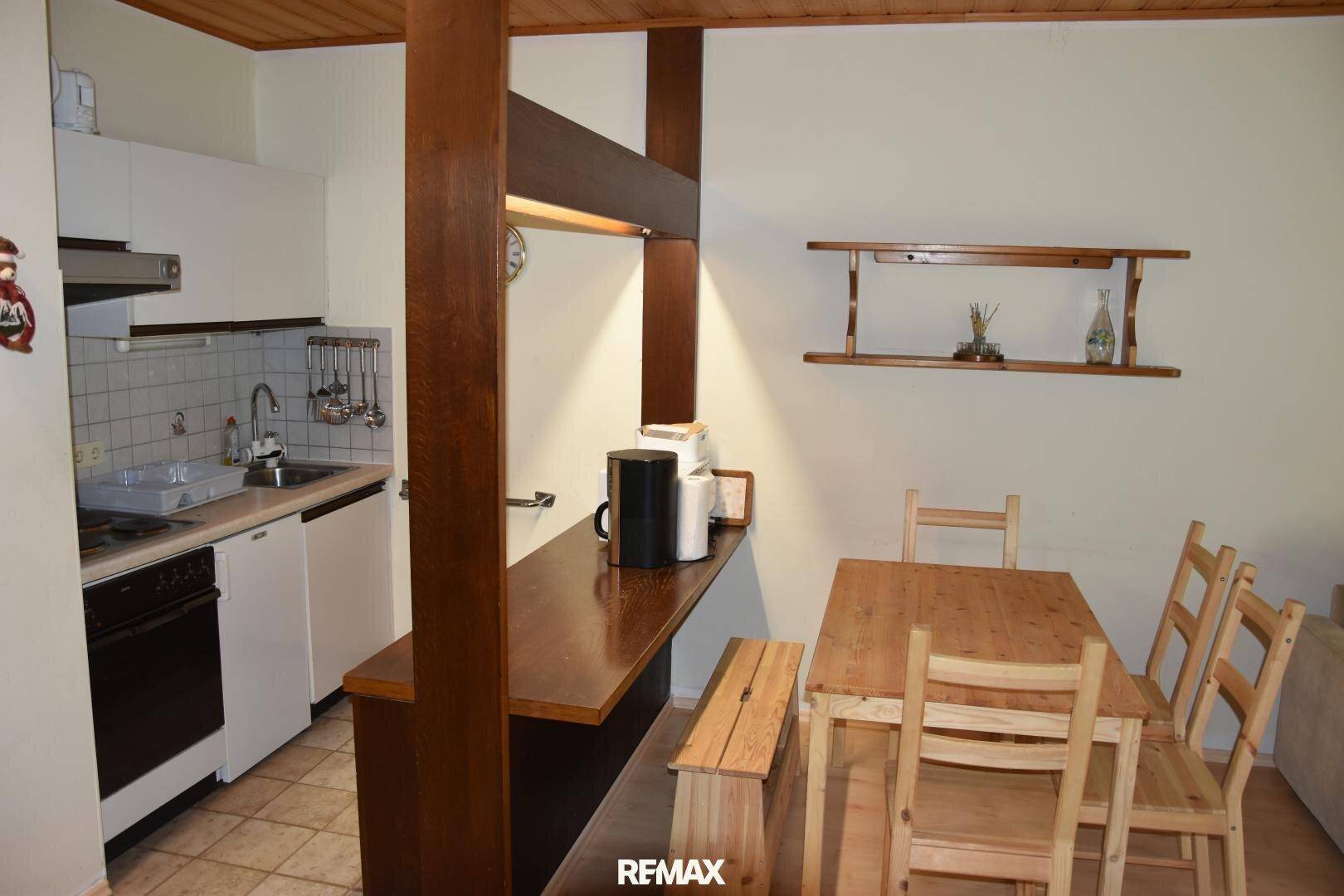 Offene Küchenzeile mit Essbereich, Holztisch und Bänken, integriert in den Wohnraum.