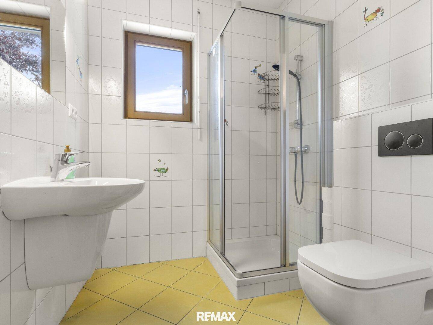 Modernes Badezimmer mit weiß gefliesten Wänden, gelbem Boden und Duschkabine.
