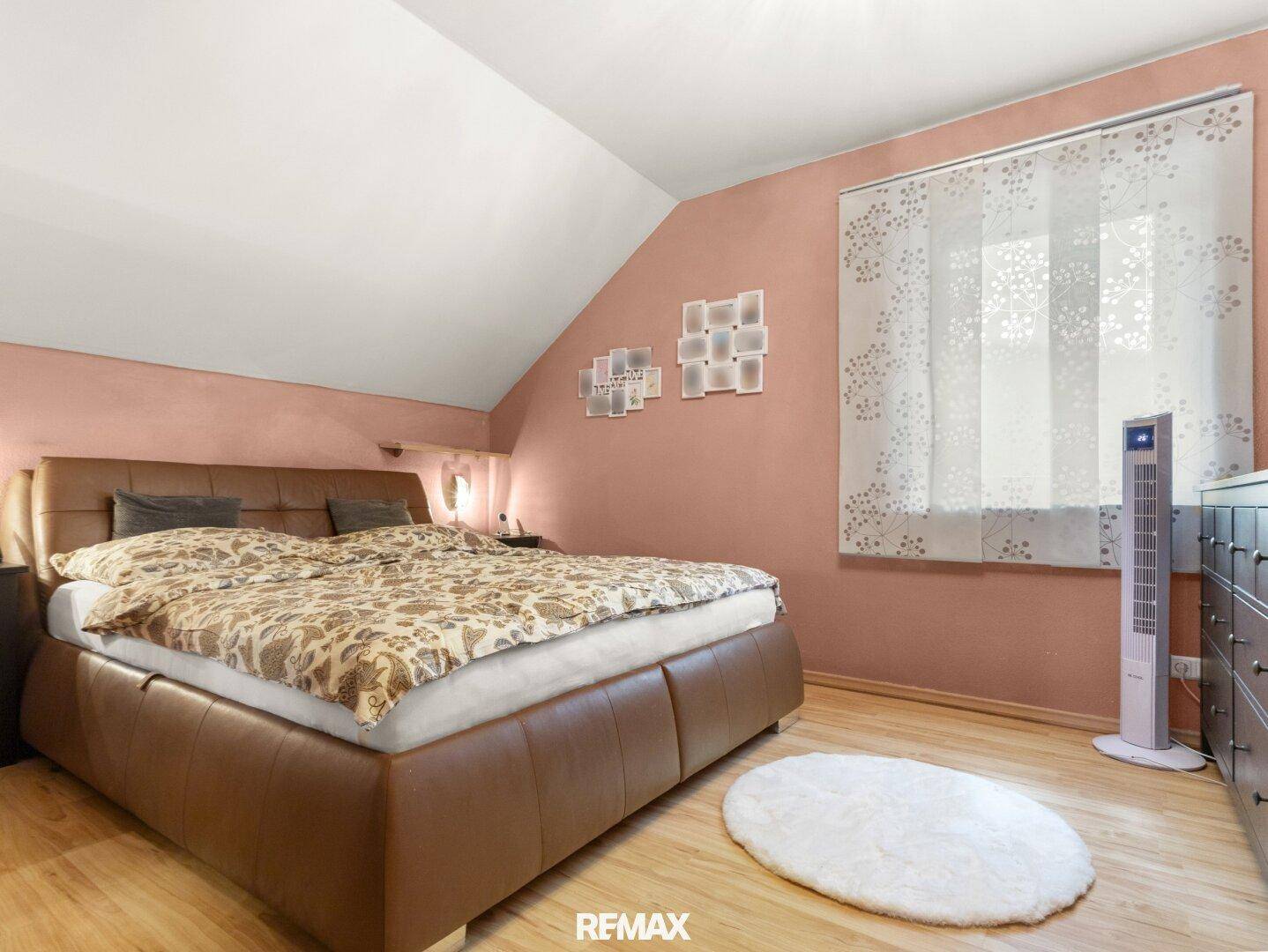 Gemütliches Schlafzimmer mit Dachschräge, Doppelbett und Holzboden.