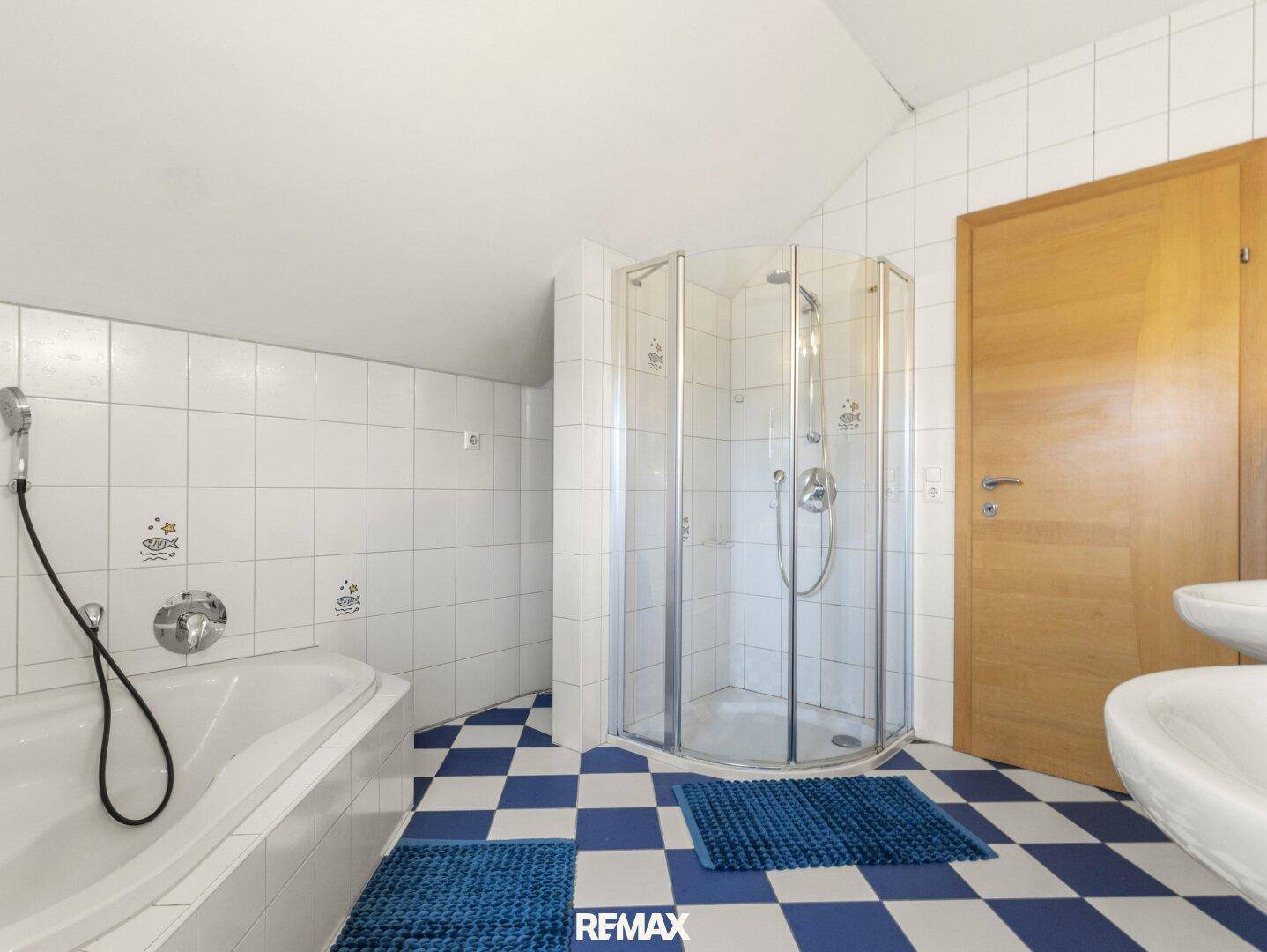 Geräumiges Badezimmer mit Badewanne, Duschkabine und blau-weiß kariertem Fliesenboden.