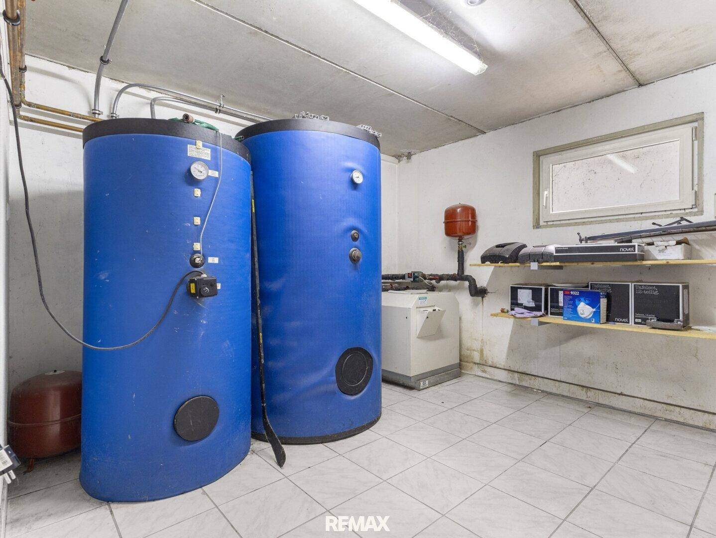 Heizungsraum im Keller mit zwei großen blauen Warmwasserspeichern und technischer Ausstattung.