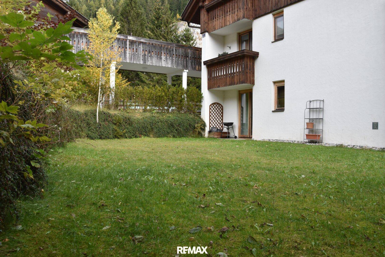 Große Rasenfläche neben dem Haus, umgeben von Bäumen und Sträuchern, ideal zum Entspannen.