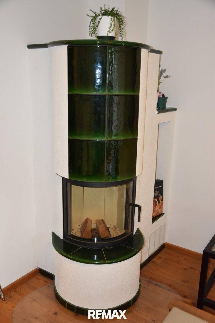 Detailaufnahme eines traditionellen grünen Kachelofens mit Holzscheiten, der Wärme und Gemütlichkeit spendet.