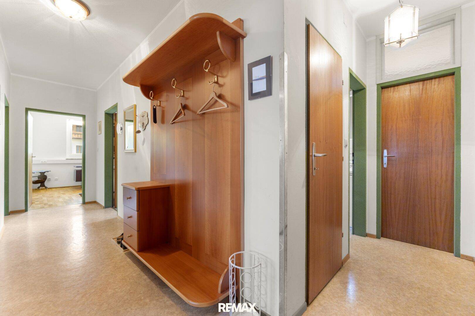 Gemütlicher Flur mit Holzgarderobe, Linoleumboden und mehreren Zimmertüren.