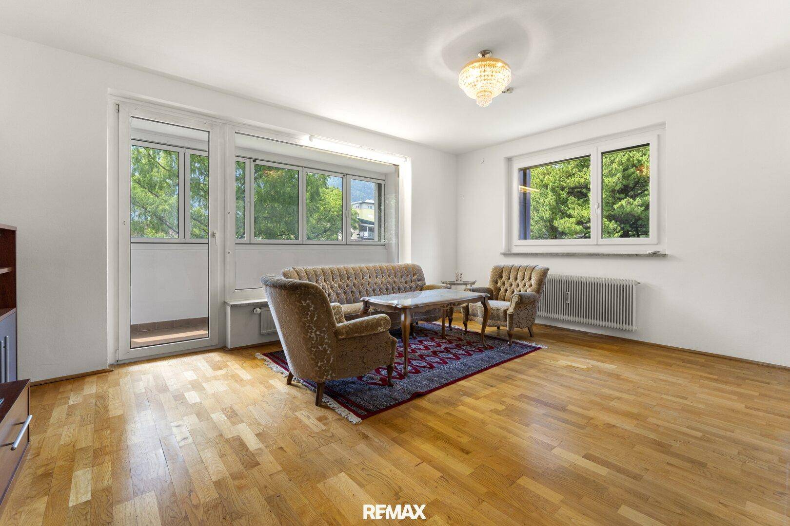 Geräumiges Wohnzimmer mit Parkettboden, Vintage-Möbeln und Zugang zum Balkon.