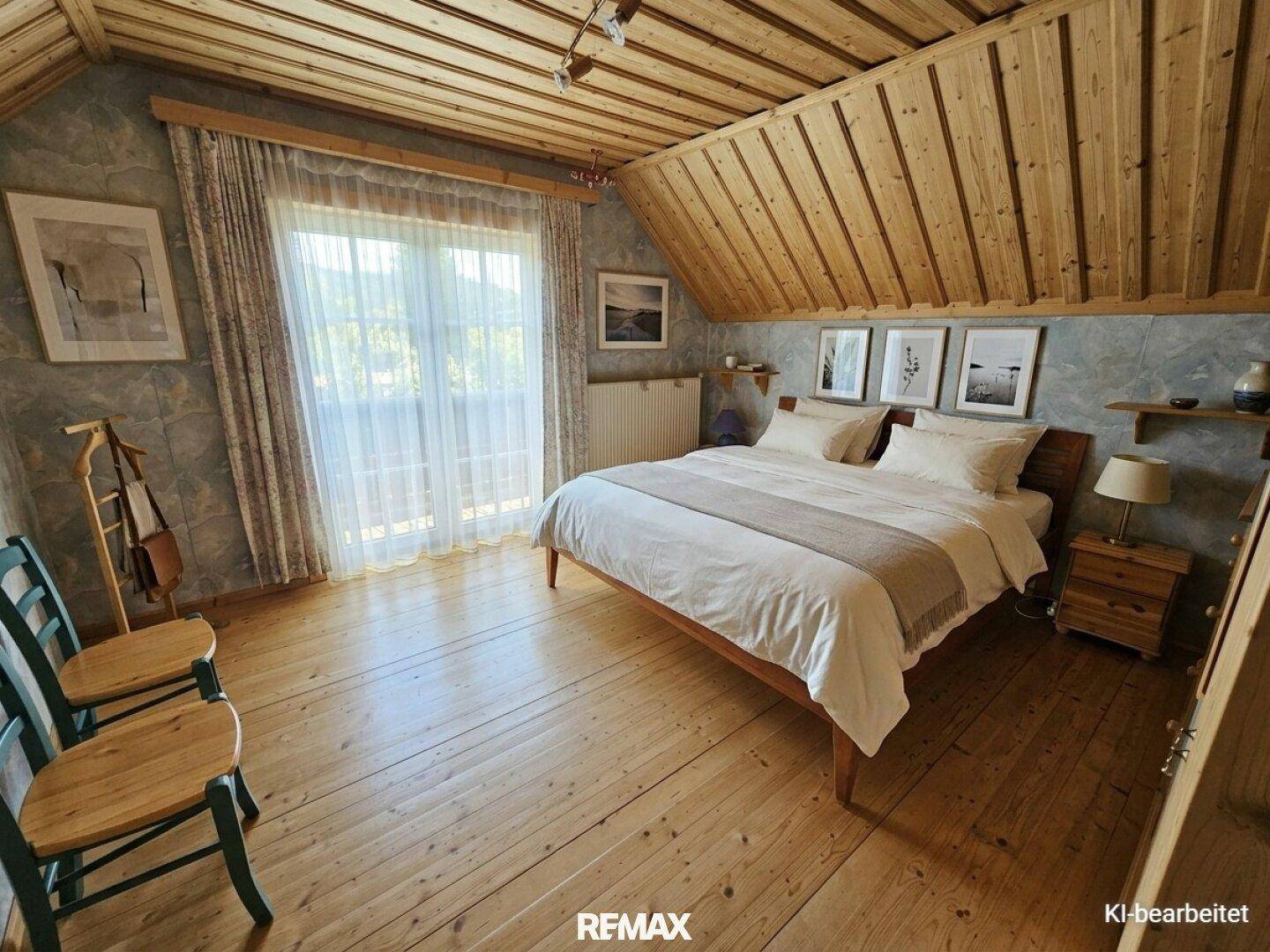 Schlafzimmer mit Holzboden, Dachschrägen und Zugang zu einem Balkon.
