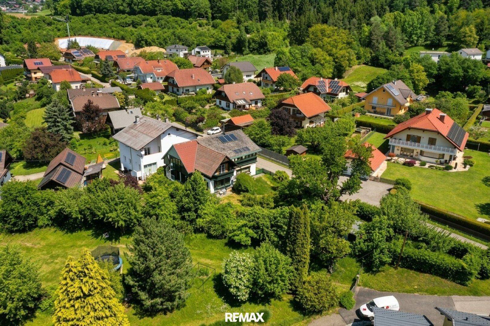 Luftaufnahme einer Wohnsiedlung mit vielen Grünflächen und Häusern mit Solaranlagen.