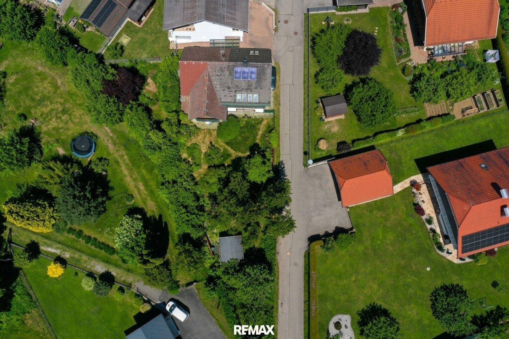 Vogelperspektive des Grundstücks mit Garten, Wegen und angrenzenden Häusern.