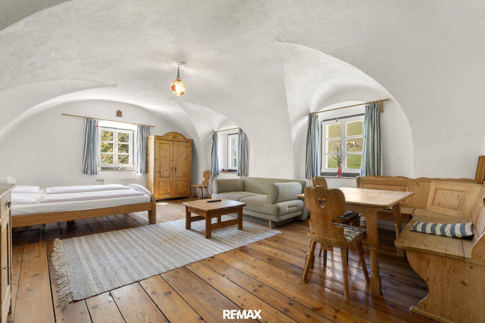 Gemütliches Wohnzimmer mit gewölbter Decke, Holzboden und traditionellen Möbeln.