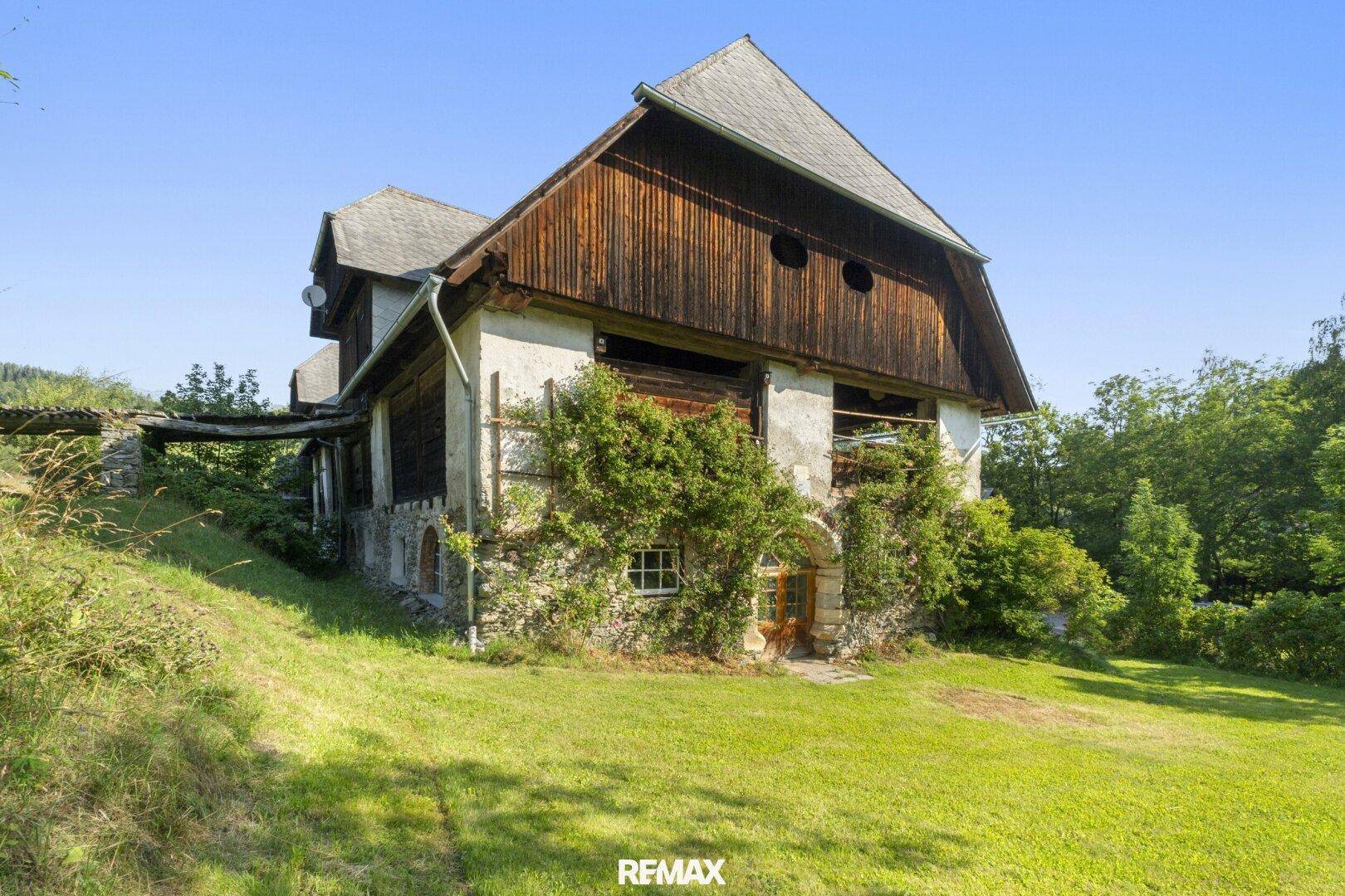 Traditionelles Bauernhaus mit Holzbalken und bewachsenen Fassaden, eingebettet in die Natur.
