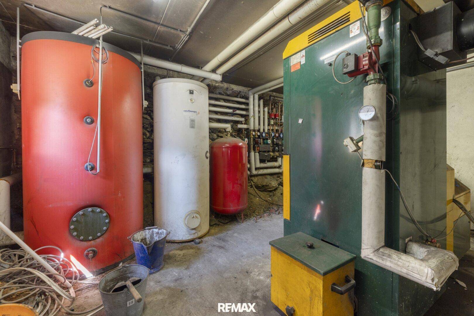 Heizungsraum im Keller mit großen Warmwasserspeichern und komplexen Rohrleitungen.