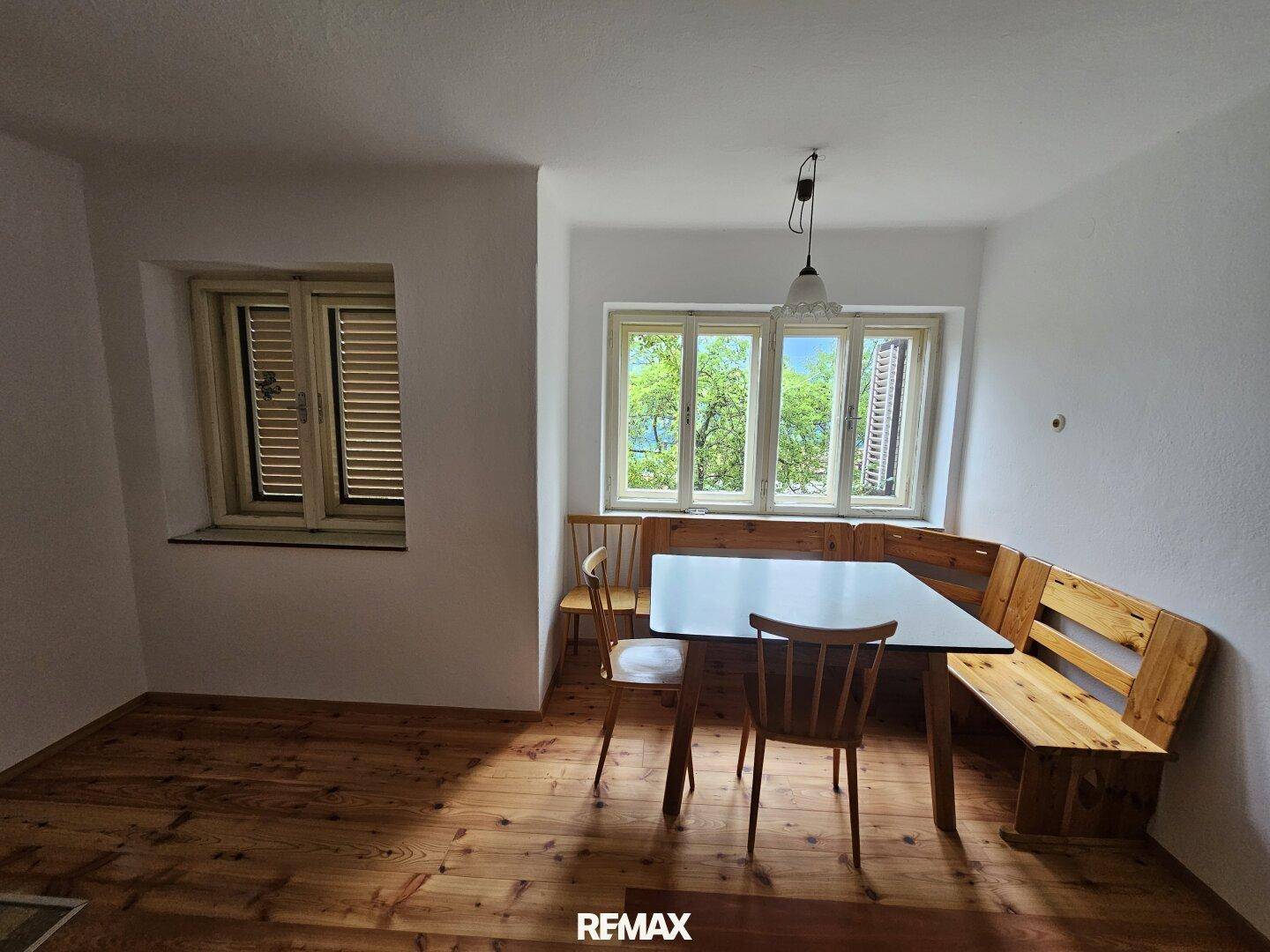Gemütlicher Essbereich mit Holzboden, eingebauter Eckbank und Fenster mit Blick ins Grüne.
