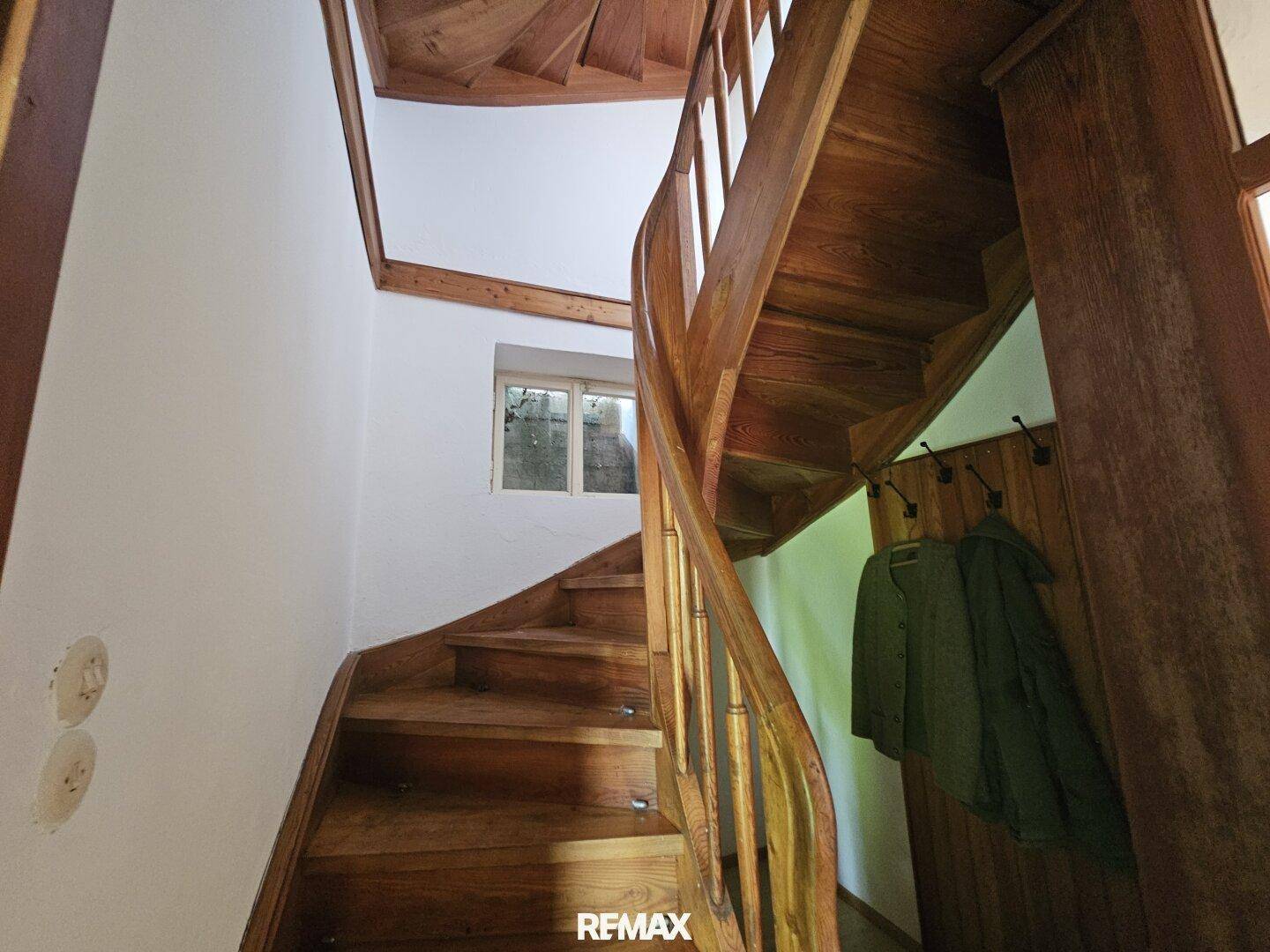 Elegante Holztreppe mit geschwungenem Geländer, die die verschiedenen Etagen miteinander verbindet.