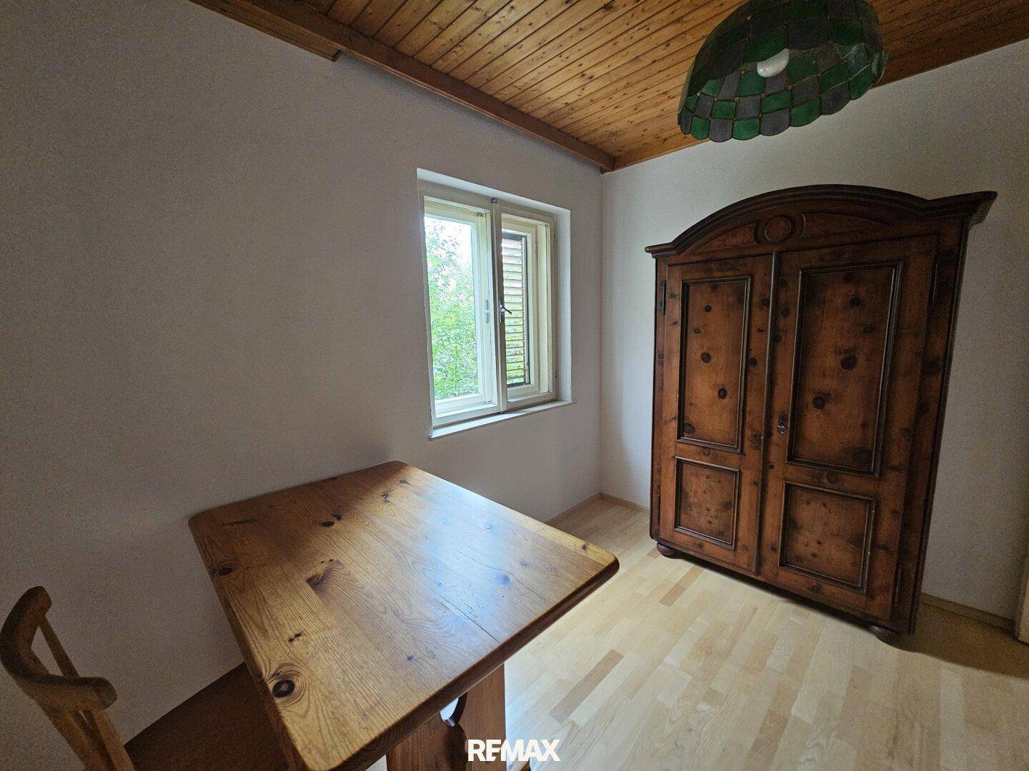 Gemütliches Zimmer mit Holzboden, rustikalem Holztisch und großem Holzschrank.