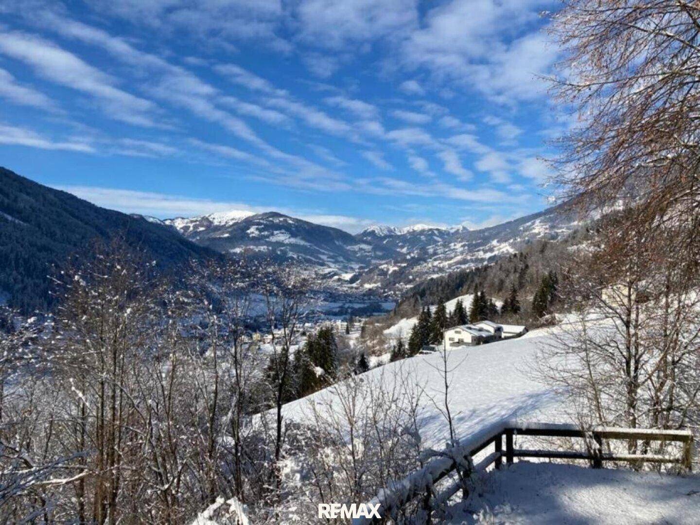Winterliche Berglandschaft mit schneebedeckten Hügeln und einem weiten Blick über das Tal.
