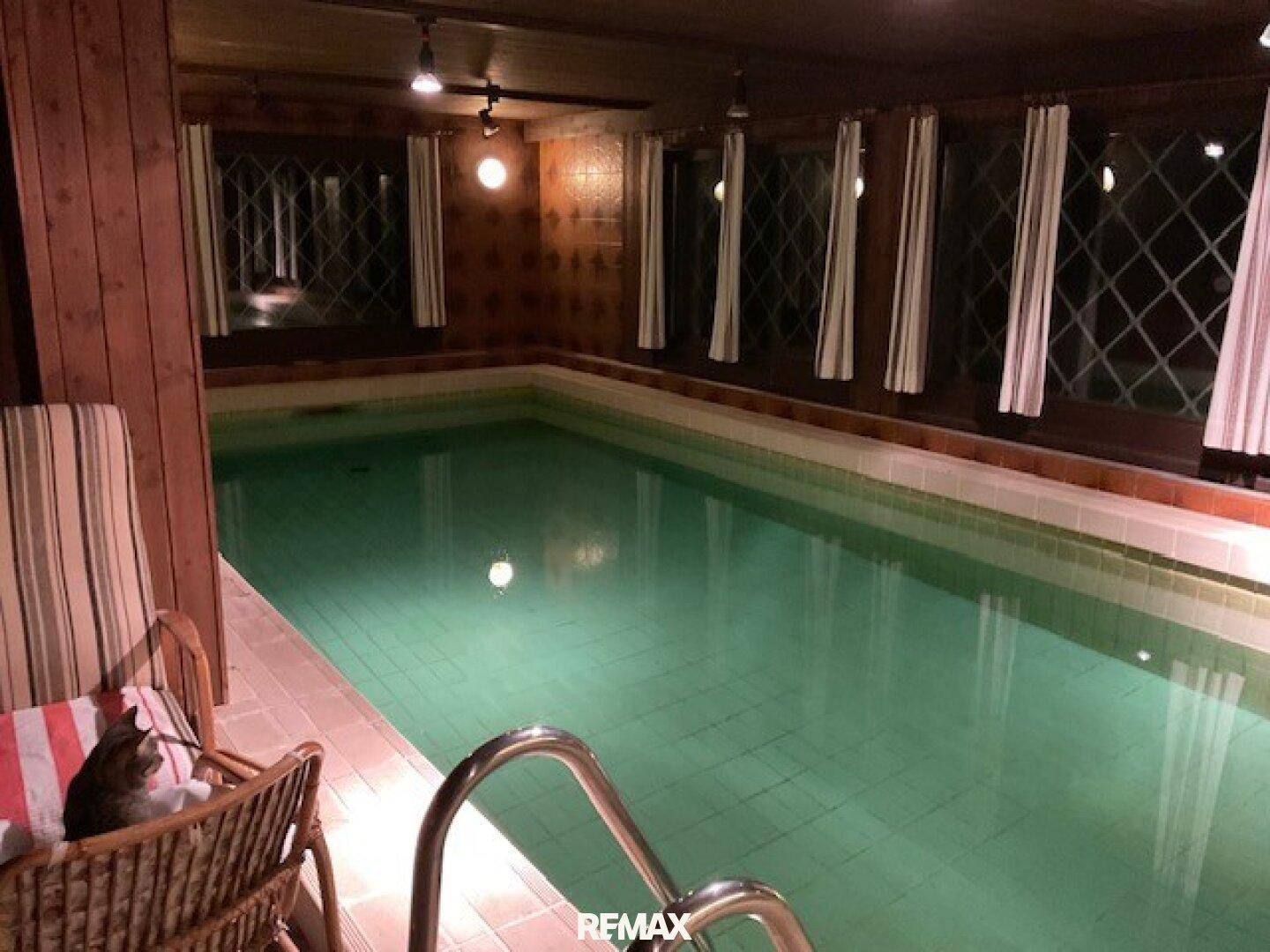 Innenpoolbereich mit Holzverkleidung und mehreren Fenstern, ideal für Entspannung und Sport.