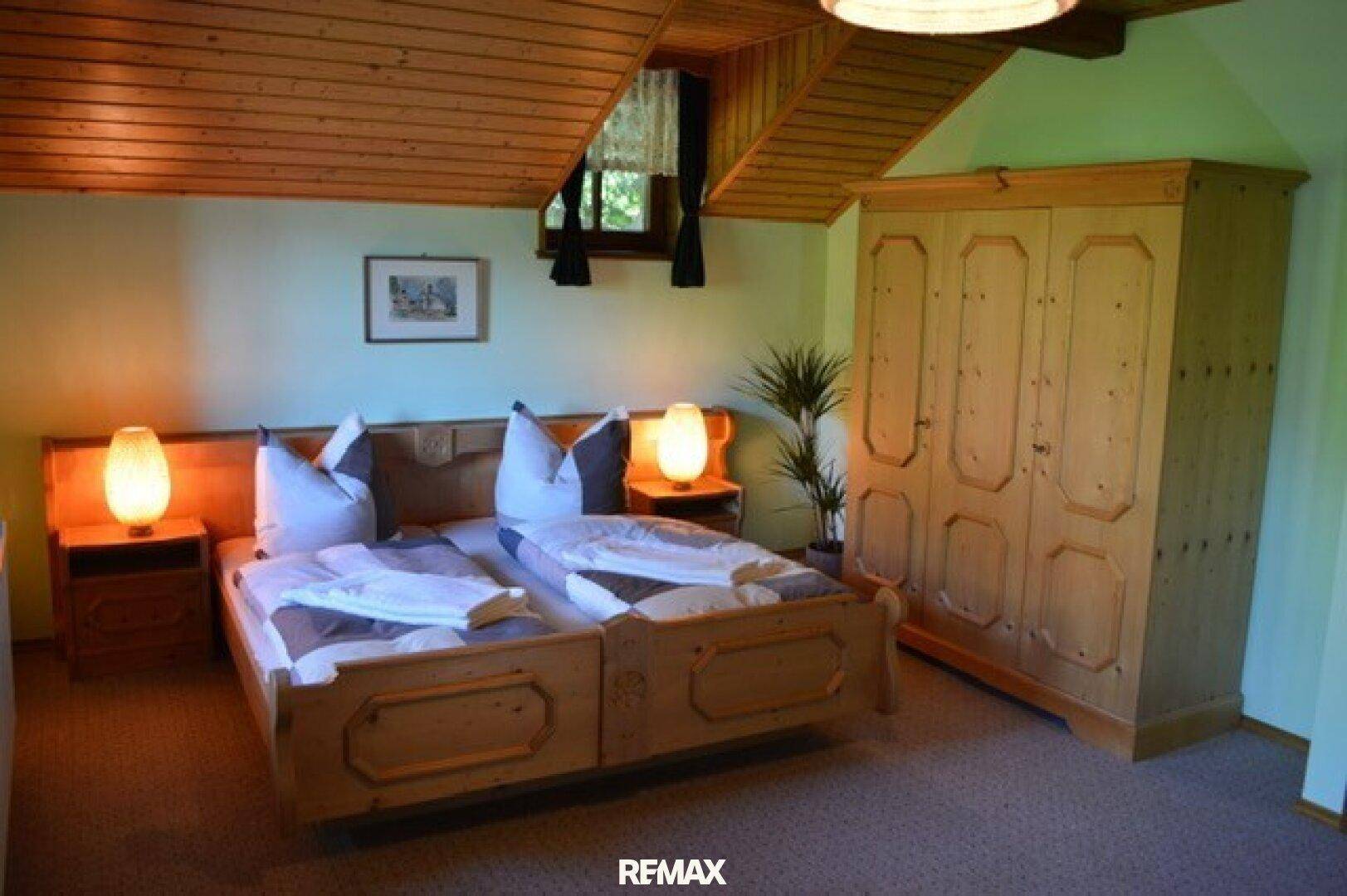 Rustikales Schlafzimmer mit Holzvertäfelung, zwei Einzelbetten und einem großen Holzschrank.