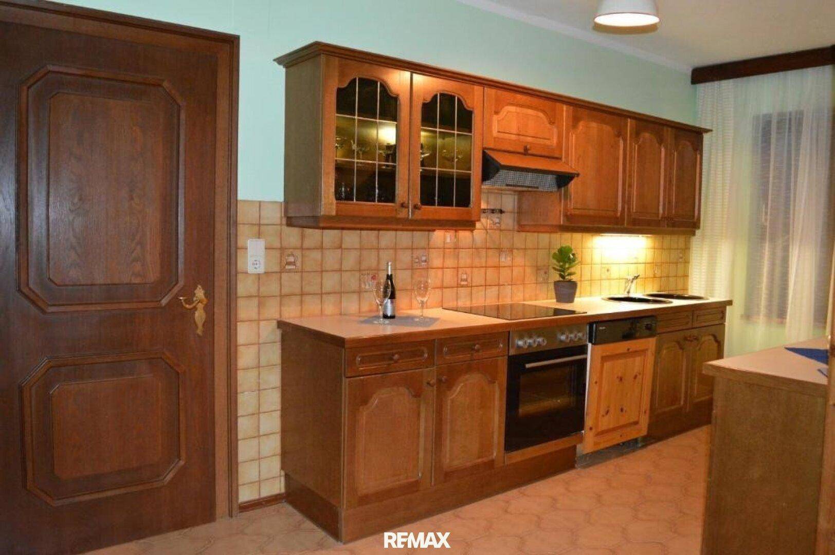 Traditionelle Holzküche mit Einbaugeräten, gefliestem Spritzschutz und einem Fenster.