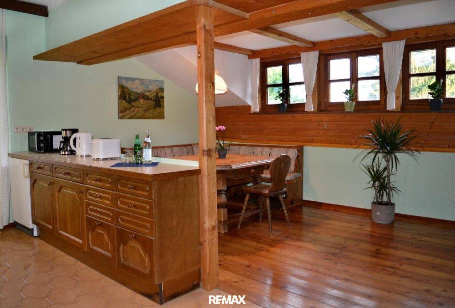 Offene Küche mit Holzelementen, integriertem Essbereich und Blick auf die grüne Umgebung.