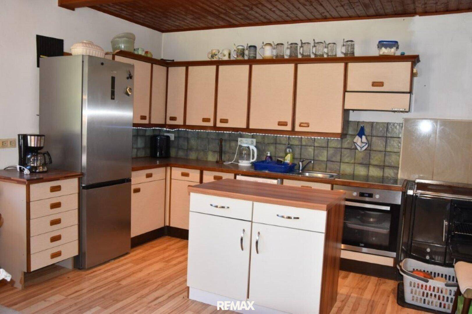 Traditionelle Küche mit beigen Schränken, Holzdecke und modernen Edelstahlgeräten.