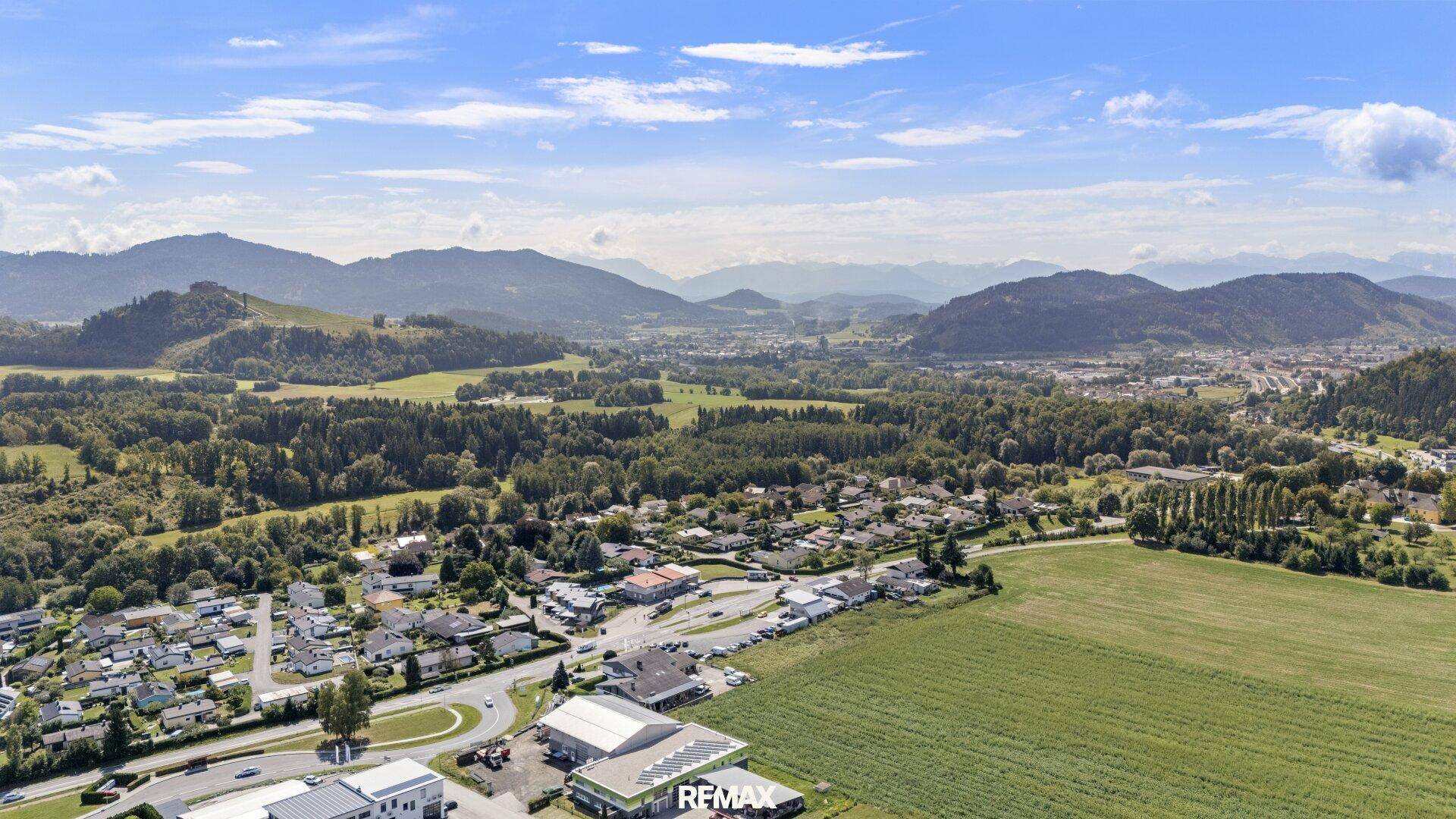 Weitläufige Luftaufnahme der malerischen Landschaft mit Bergen, Feldern und einer Siedlung im Tal.