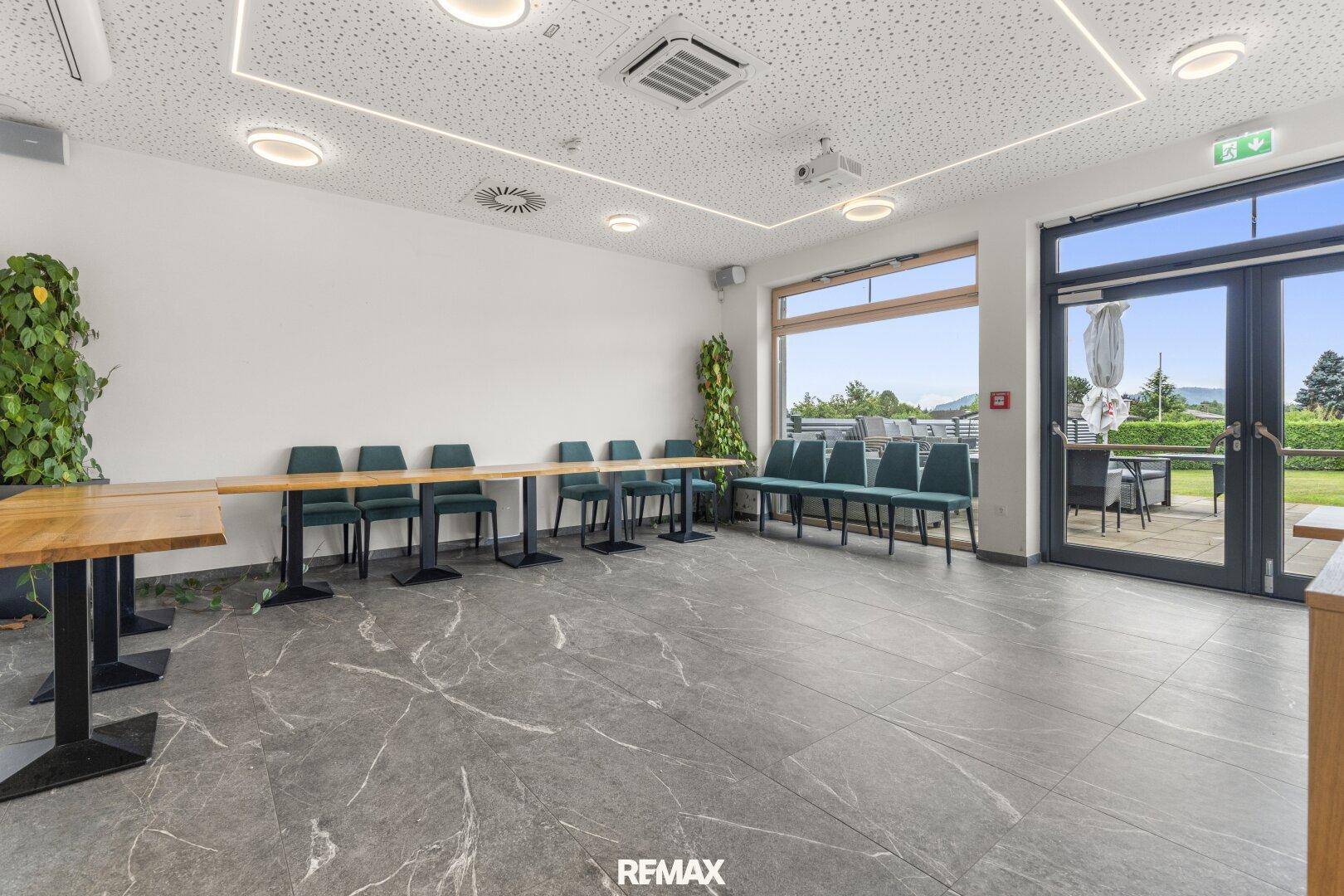Geräumiger Konferenzraum mit flexibler Bestuhlung, großen Fenstern und einem Projektor für Präsentationen.