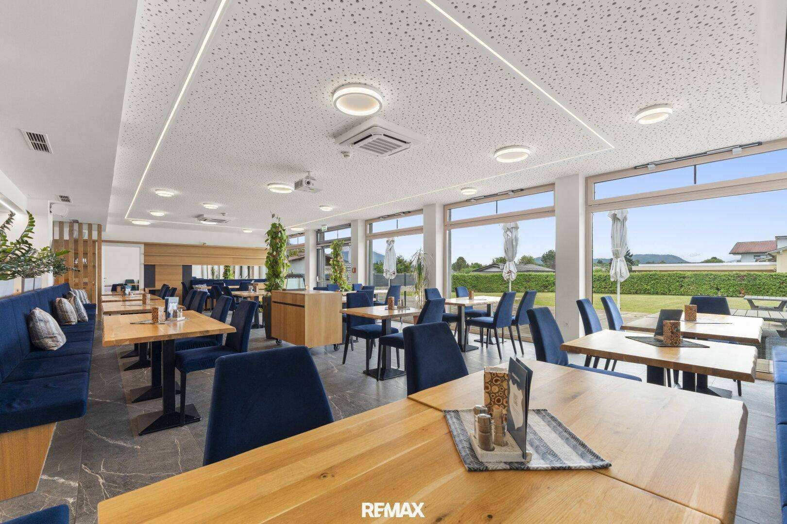 Heller Speisesaal mit Panoramablick auf die grüne Außenanlage durch die großen Fensterfronten.