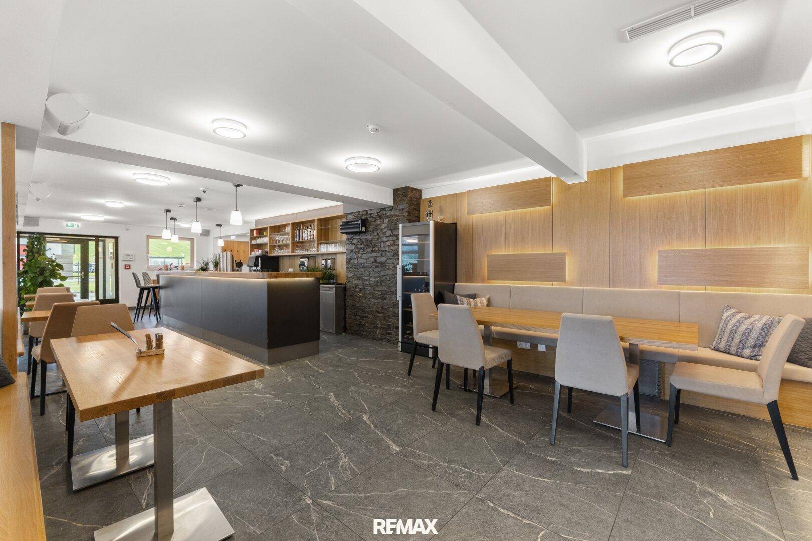 Gemütlicher Restaurantbereich mit eleganter Holzwandverkleidung, integrierten Sitzbänken und modernen Tischen.