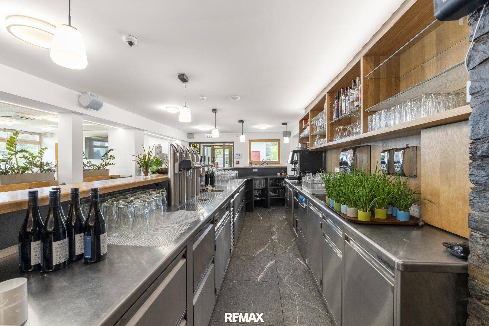 Blick hinter die Bar mit professioneller Edelstahlausstattung, Zapfanlage und Gläserregalen für den Service.