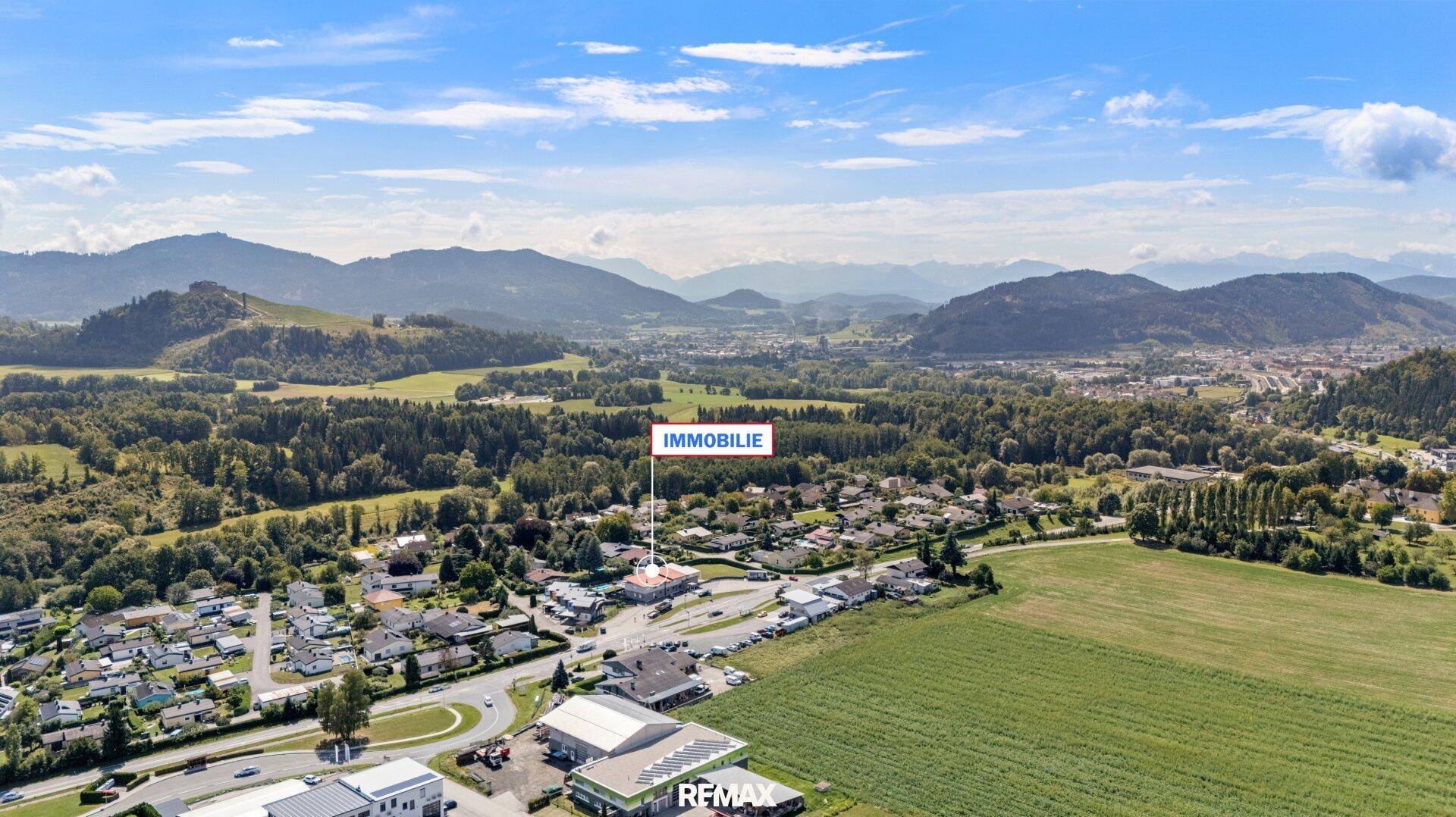 Luftaufnahme mit Markierung der Immobilie in der weiten Landschaft mit Bergen und Siedlungen.