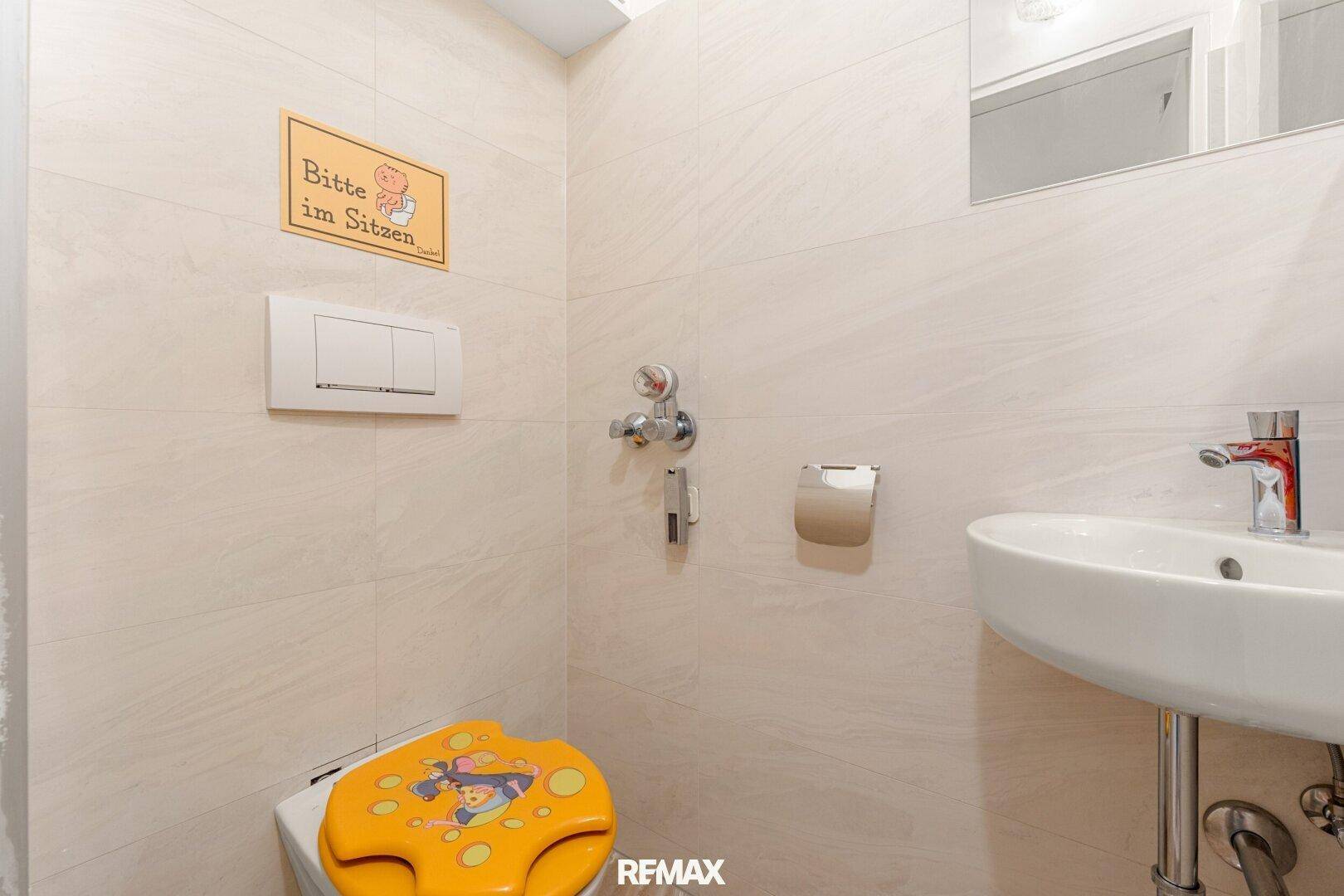 Kleines Gäste-WC mit hellem Fliesenboden und Wand-WC.
