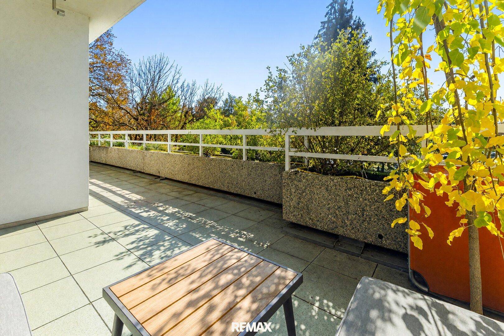 Geräumige Terrasse mit Fliesenboden und Blick ins Grüne.