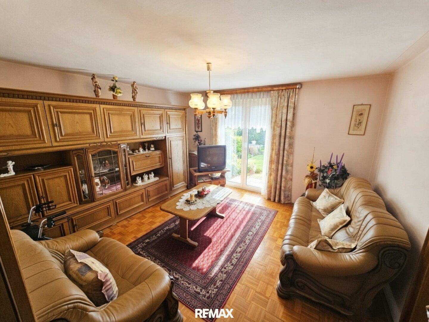 Geräumiges Wohnzimmer mit traditionellen Holzmöbeln, bequemen Sofas und Zugang zum Garten.