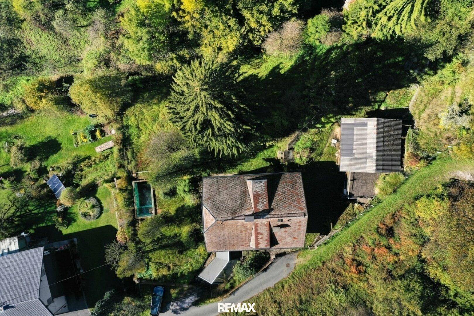 Luftaufnahme des Anwesens mit Haus, Nebengebäude, Pool und umgebender Wald- und Wiesenlandschaft.
