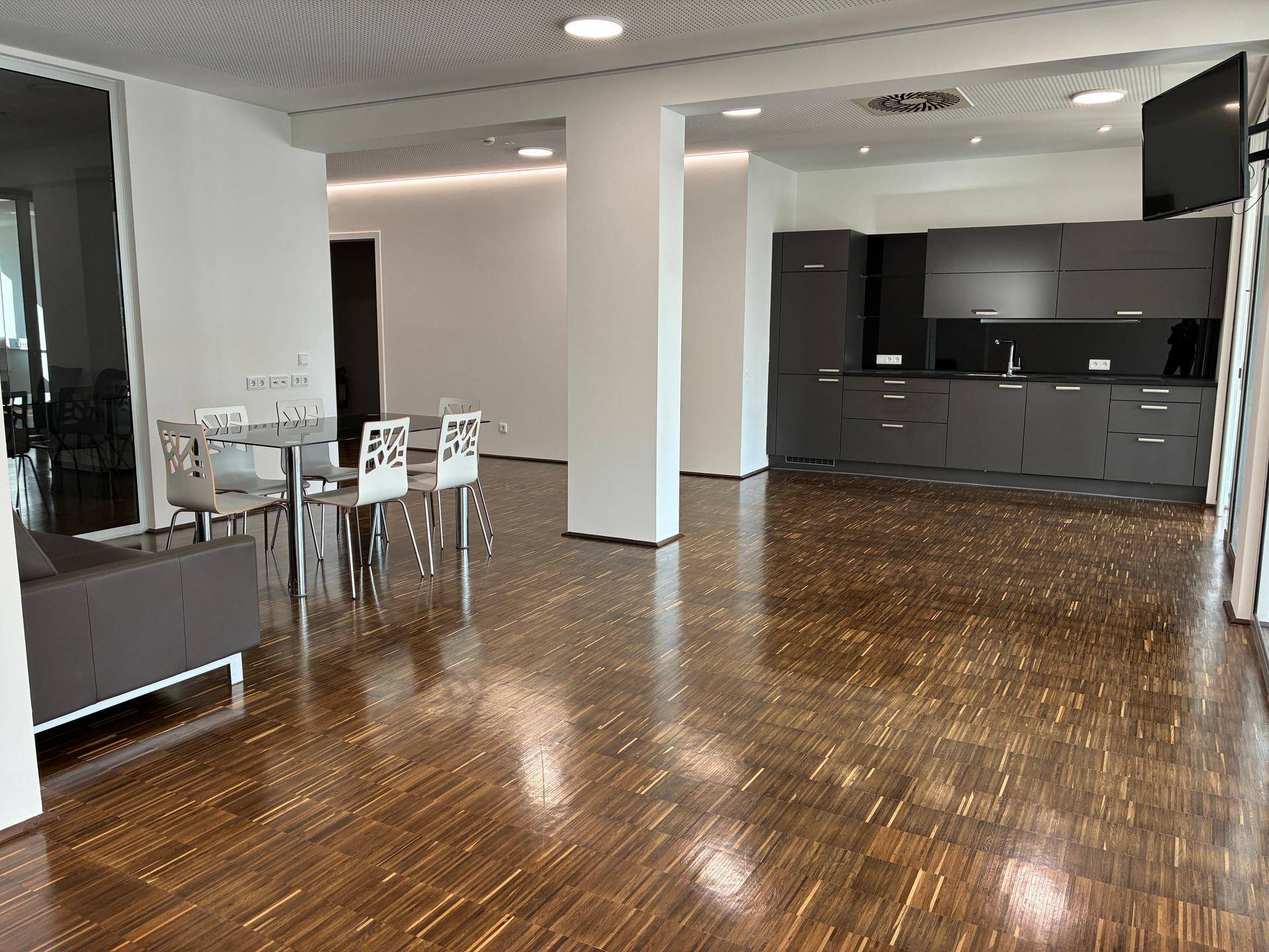 Moderner offener Bereich mit Küchenzeile, Esstisch und Lounge-Sofa, perfekt für gemeinsame Pausen.