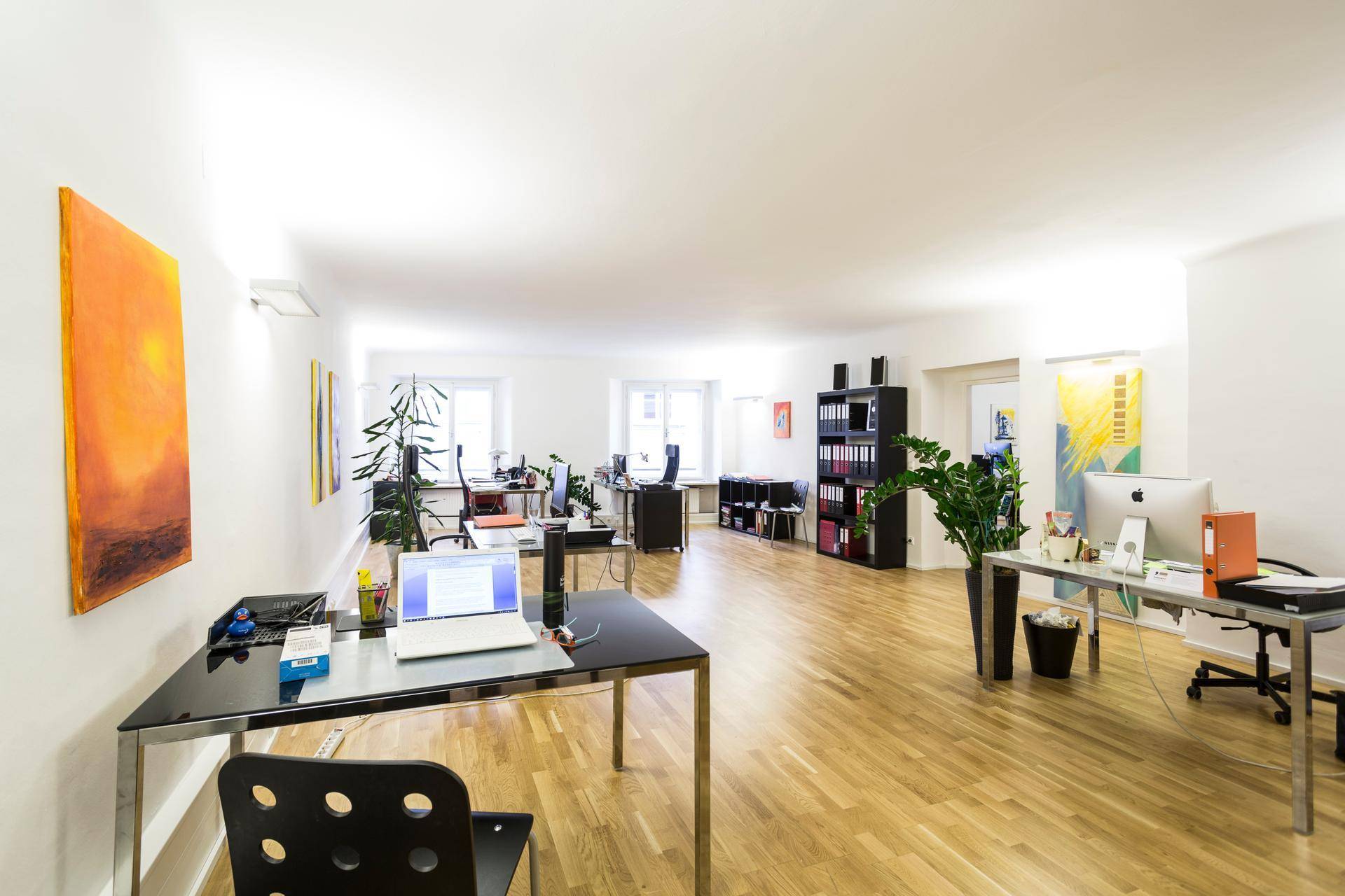 Großzügiger, offener Bürobereich mit mehreren Arbeitsplätzen, Holzboden und viel Tageslicht.