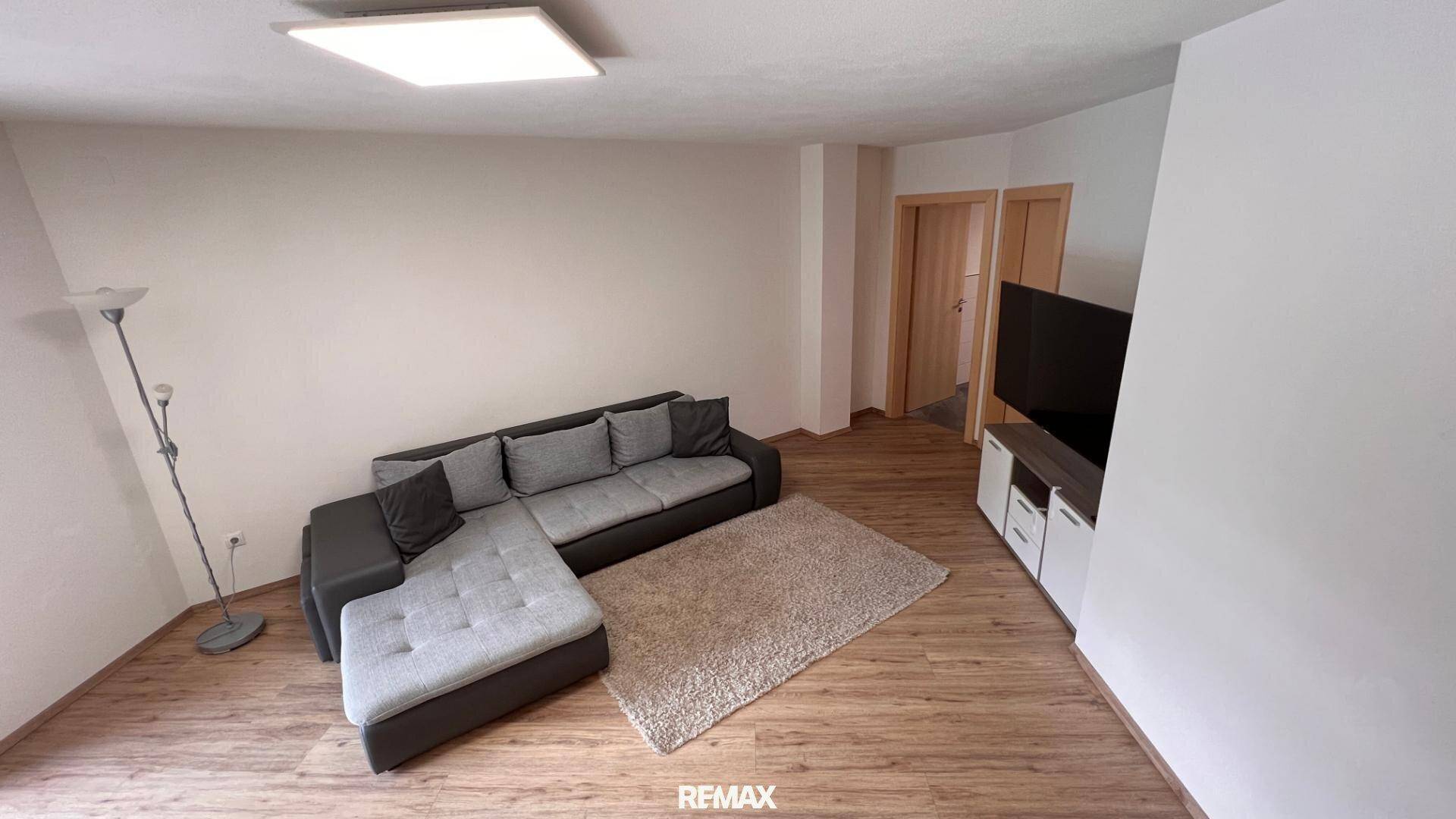 Geräumiges Wohnzimmer mit Ecksofa, Teppich und Holzboden.
