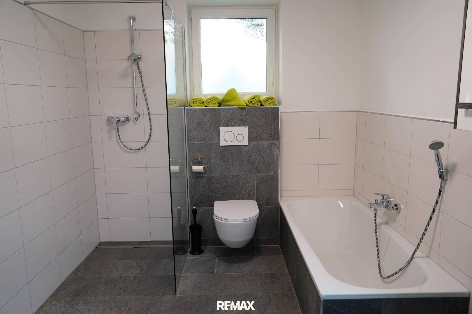 Helles Badezimmer mit großer Dusche, Badewanne und modernen Fliesen.