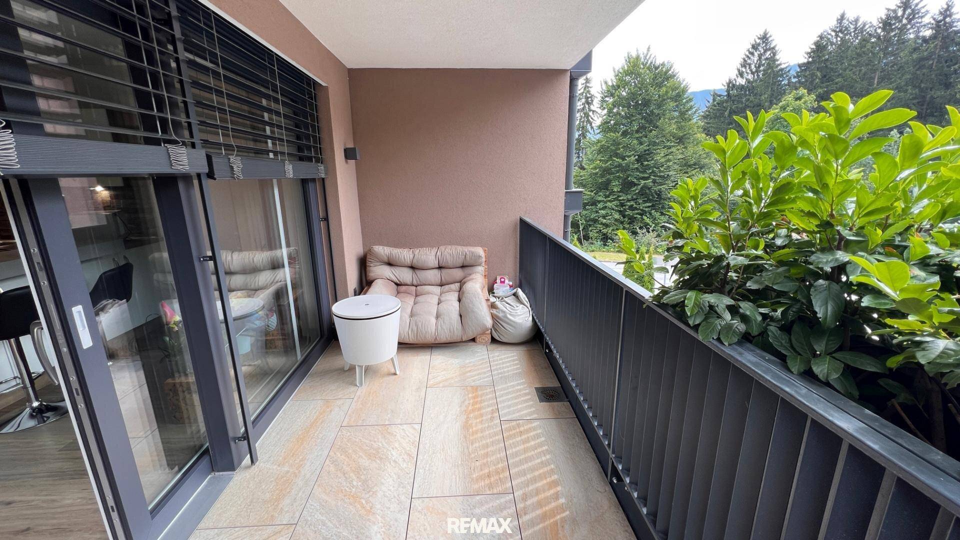 Gemütlicher Balkon mit Fliesenboden, Sitzgelegenheiten und Blick ins Grüne.