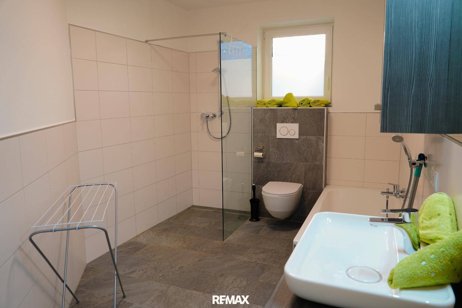 Modernes Badezimmer mit Dusche, Badewanne, WC und Fenster.
