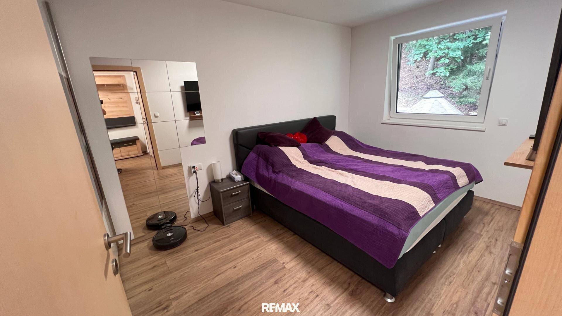 Schlafzimmer mit Holzboden, großem Bett und Spiegelschränken.