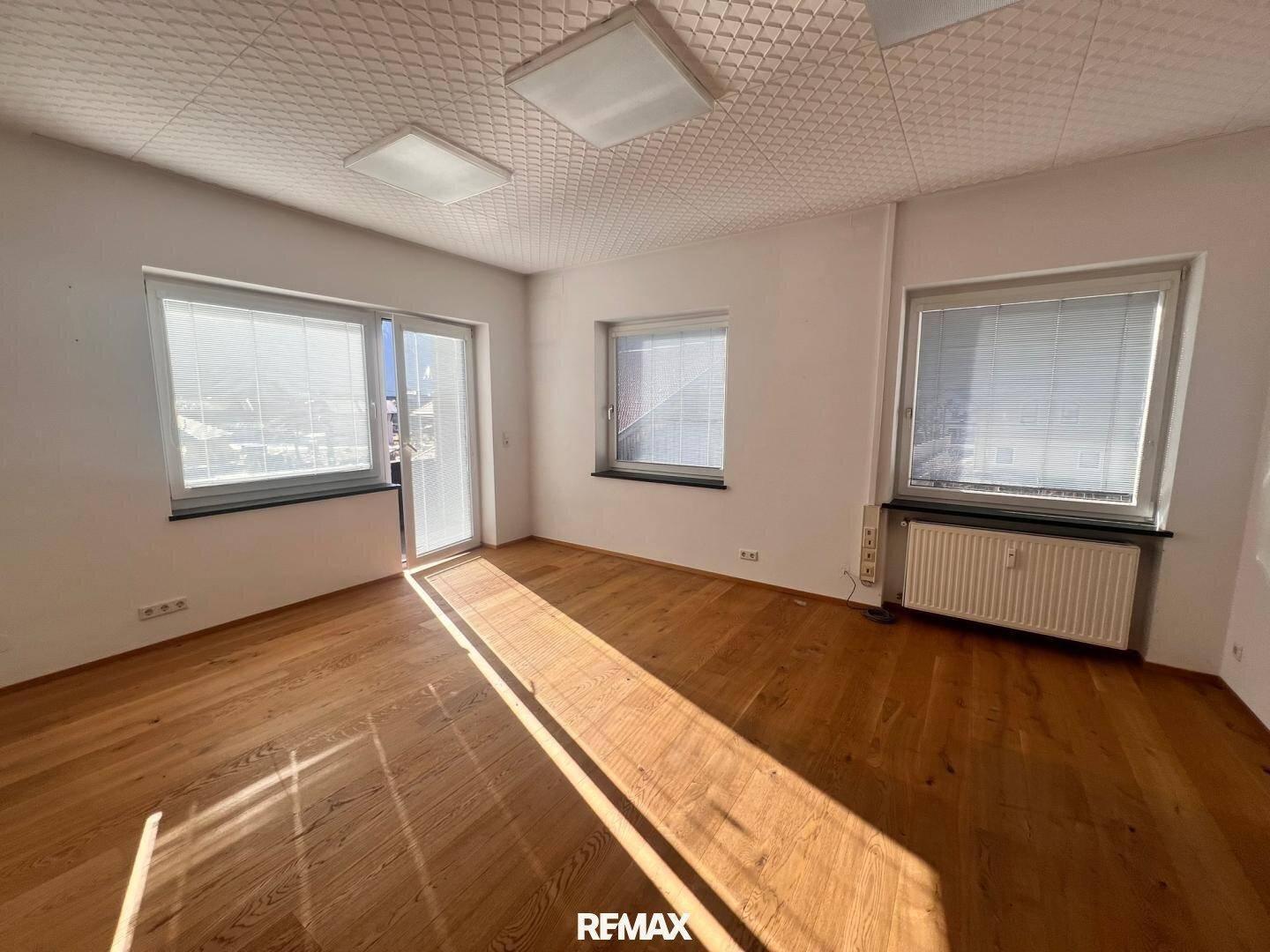 Heller Büroraum mit Holzboden, großen Fenstern und viel Tageslicht, bereit zur individuellen Gestaltung.