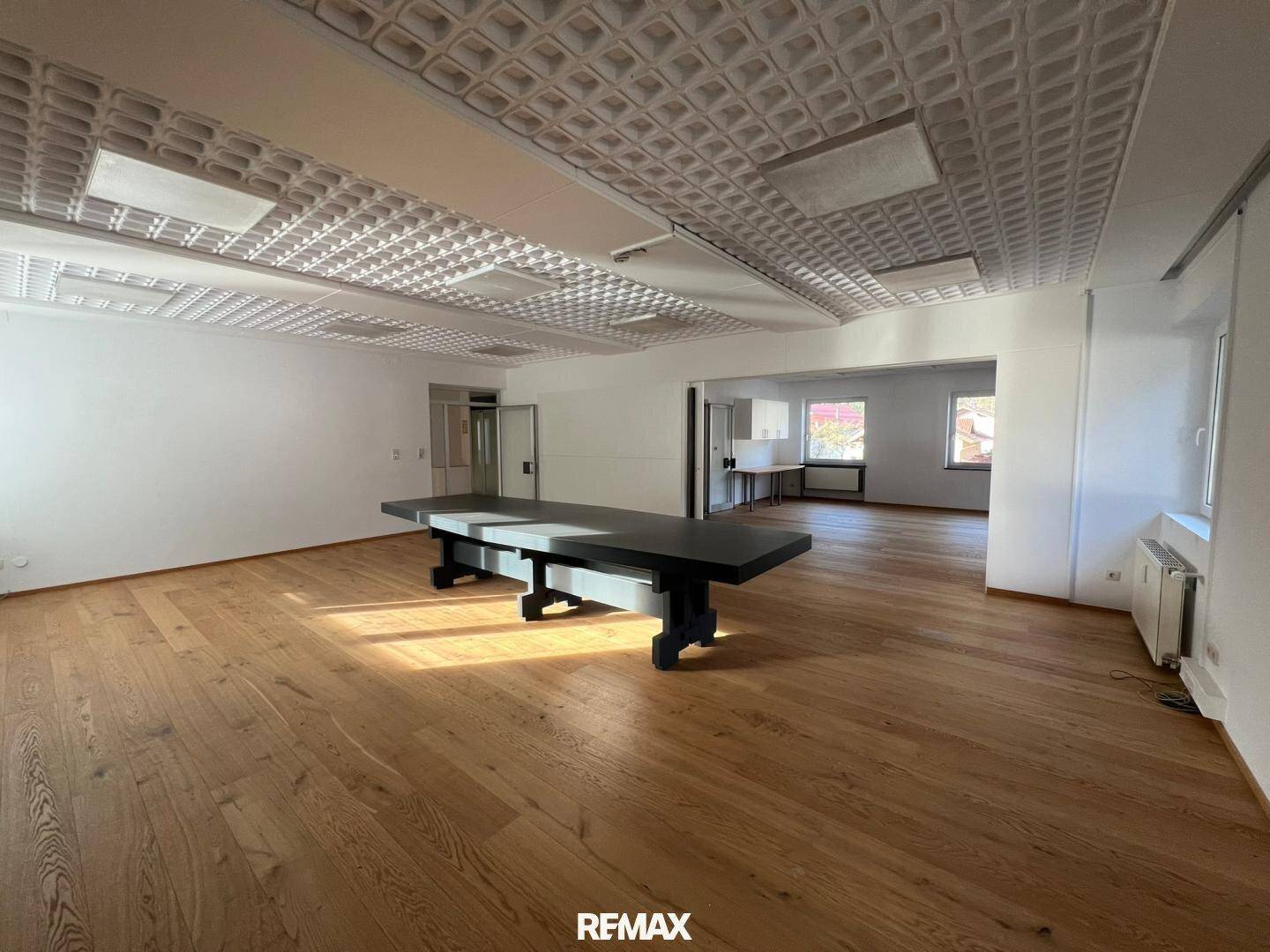 Großer, offener Bürobereich mit Holzboden und einem langen Tisch, ideal für Besprechungen oder Coworking.