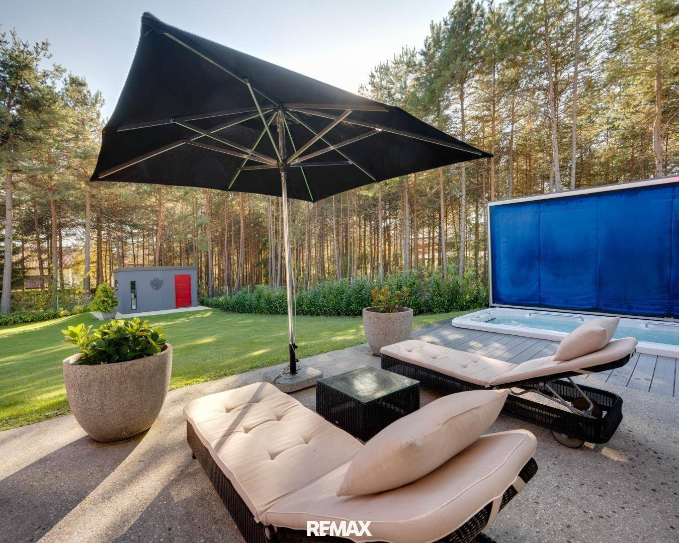 Sonniger Terrassenbereich mit Liegestühlen, großem Sonnenschirm und integriertem Whirlpool.