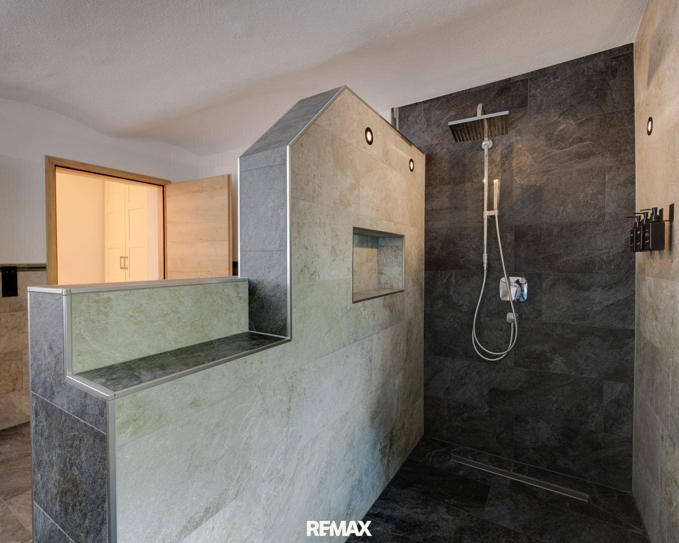 Geräumige begehbare Dusche mit modernen Fliesen in Grau- und Beigetönen.