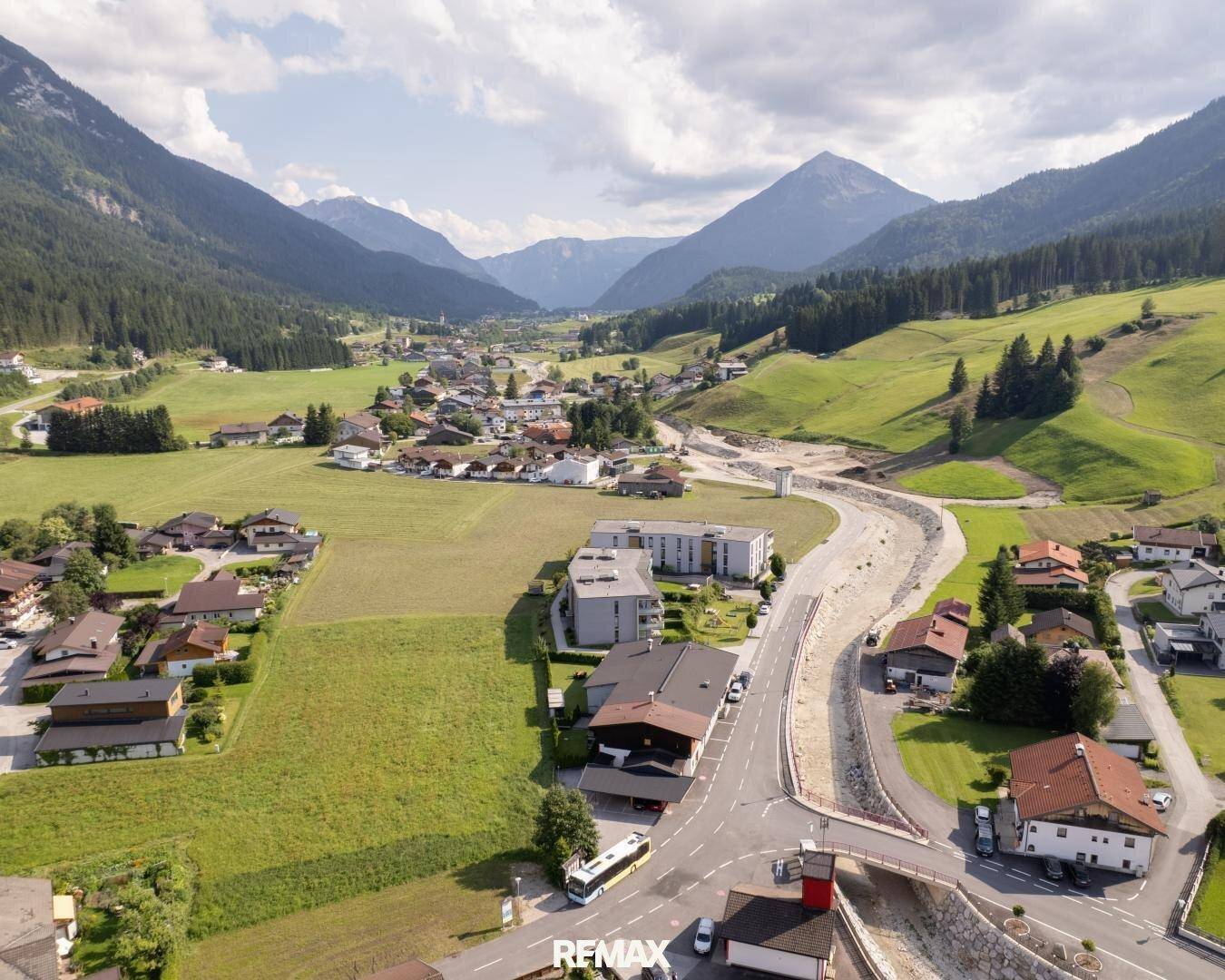 Malerische Luftaufnahme eines Dorfes in einem grünen Tal, umgeben von Bergen und Natur.
