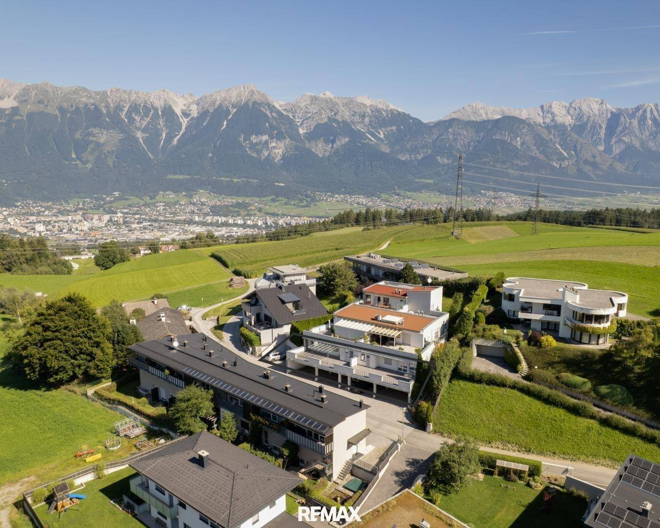 Weitläufige Wohnsiedlung in grüner Umgebung mit beeindruckendem Alpenpanorama im Hintergrund.