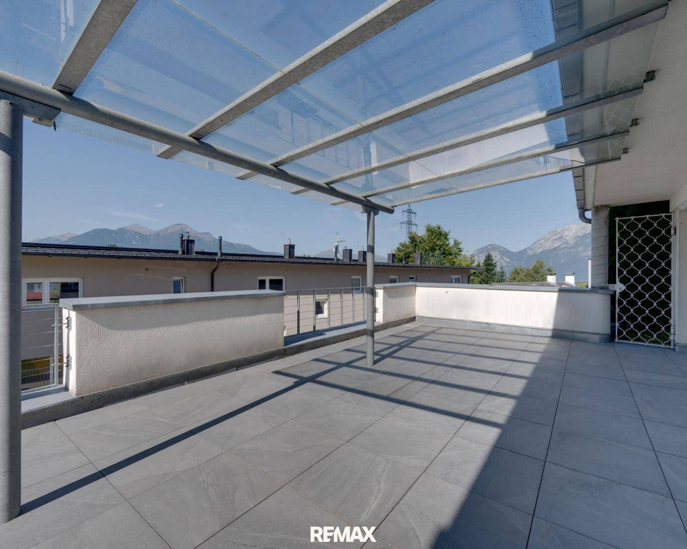 Teil der Terrasse mit transparenter Glasüberdachung und freiem Blick auf die Berglandschaft.