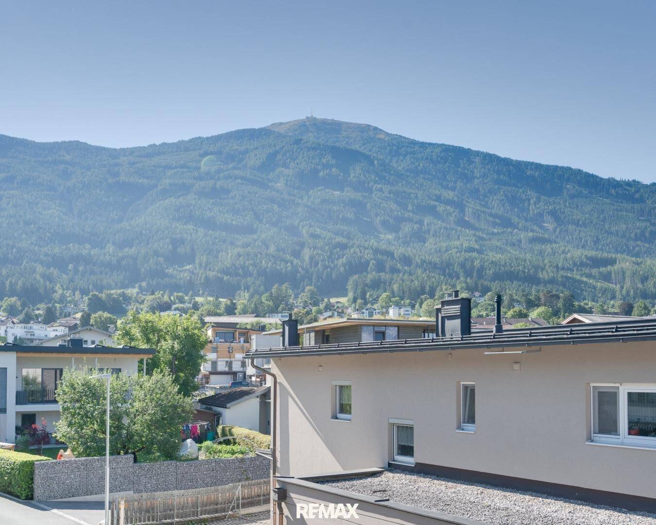 Malerischer Ausblick auf bewaldete Berge und die Dächer der umliegenden Häuser.